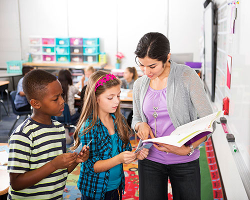 A teacher showing a passage to two students.
